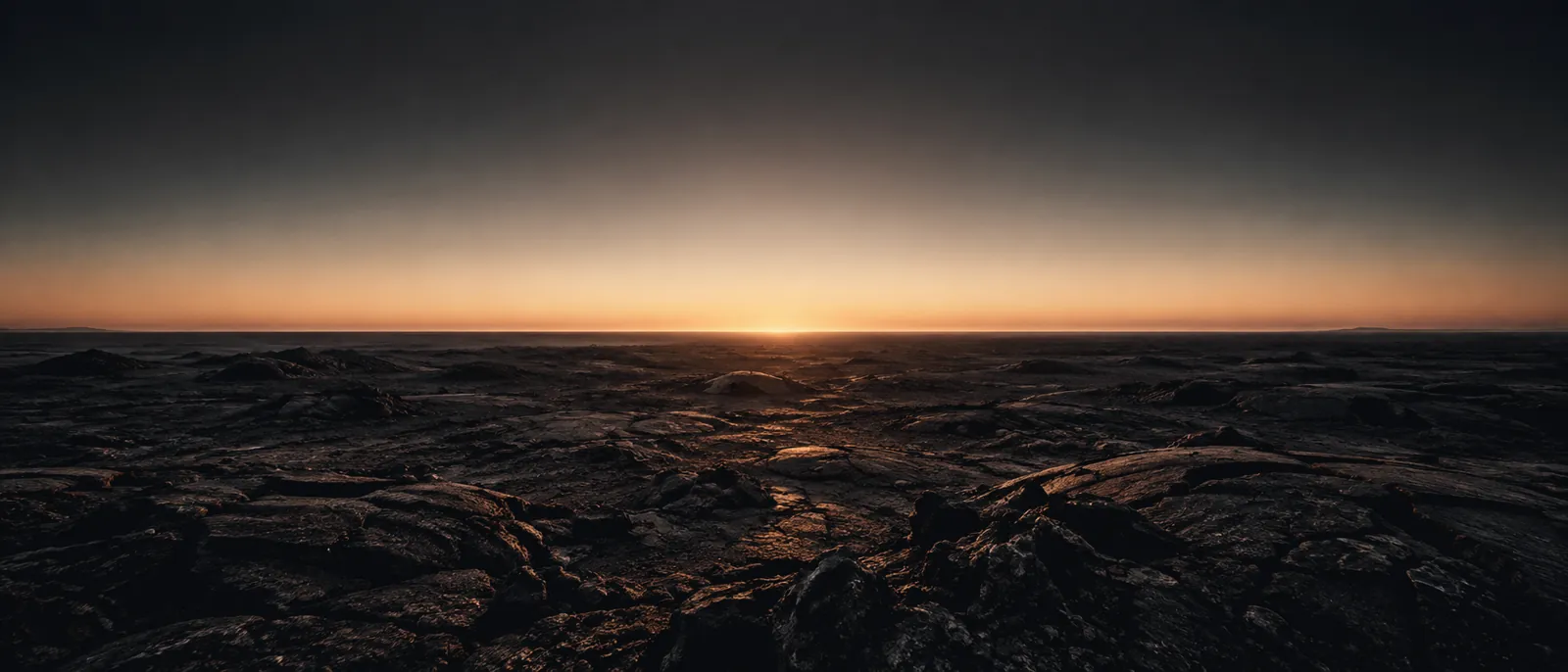 Um planalto vulcânico escuro que se estende até um horizonte reto, iluminado pela primeira luz do dia.